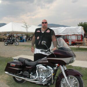 A man standing next to a motorcycle in front of tents.